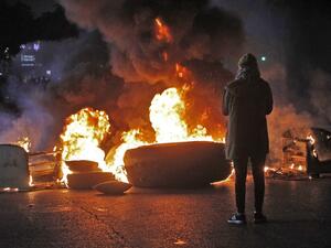 A protester stands by a flaming roadblock in the southern Lebanese city of Sidon early on December 17, 2019. Mahmoud ZAYYAT / AFP