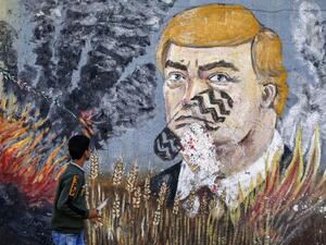 A boy looks at a graffiti mural depicting US President Donald Trump  (AFP)