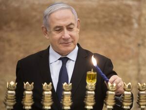 Israeli Prime Minister Benjamin Netanyahu lights a Hanukkah candle at the Western Wall, Judaism's holiest prayer site, in the Old City of Jerusalem on December 22, 2019. Sebastian Scheiner / POOL / AFP