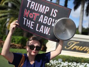 Aileen Ortega joins with other protesters outside of the Trump National Doral golf resort urging congress to impeach President Donald Trump (AFP)