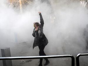 An Iranian woman raises her fist amid the smoke of tear gas at the University of Tehran during a protest driven by anger over economic problems, in the capital Tehran. (AFP/ File Photo)