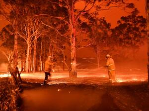 This timed-exposure image shows firefighters hosing down trees as they battle against bushfires around the town of Nowra in the Australian state of New South Wales on December 31, 2019. Thousands of holidaymakers and locals were forced to flee to beaches in fire-ravaged southeast Australia on December 31, as blazes ripped through popular tourist areas leaving no escape by land. Saeed KHAN / AFP