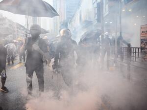 In this picture taken on August 25, 2019, Abby (centre R), 19, and her boyfriend Nick (centre L, holding tongs), 20, react after police fired tear gas during a protest in Tsuen Wan, an area in the New Territories in Hong Kong. ANTHONY WALLACE / AFP