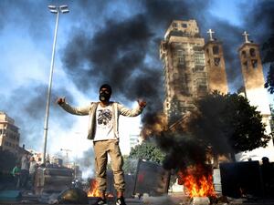 A Lebanese anti-government protester gestures next to burning garbage bins set up to block a road in the capital Beirut, on January 14, 2020. Lebanese protesters resumed blocking major highways in what they said would be a "week of wrath" demanding an end to a nearly three-month political vacuum. Although protests had declined in size in recent weeks, demonstrations have been ongoing since October, increasingly targeting banks and state institutions blamed for driving the country towards collapse. PATRICK B