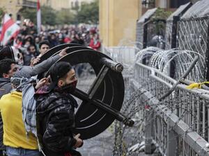 Anti-government protesters attempt to break through the security barrier in the central downtown district of the Lebanese capital Beirut near the parliament headquarters during clashes with security forces on January 18, 2020. ANWAR AMRO / AFP