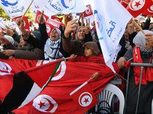 Tunisians wave their national flag and the flag of the Ennahda Islamist party as they gather on Habib Bourguiba Avenue in Tunis on January 14, 2018. AFP
