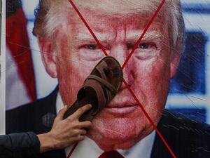 A Palestinian protester sticks his footwear on a poster depicting the face of US President Donald Trump during a demonstration against Trump's Middle East peace proposal in Khan Yunis in the southern Gaza Strip on February 3, 2020. SAID KHATIB / AFP