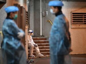 Medical personnels wearing protective suits stay near a block's entrance in the ground of a residential estate, in Hong Kong, early on February 11, 2020, after two people in the block were confirmed to have contracted the coronavirus according to local newspaper reports. Anthony WALLACE / AFP