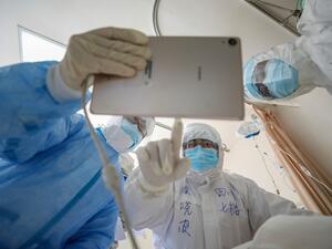 This photo taken on February 16, 2020 shows a doctor looking at an image as he checks a patient who is infected by the COVID-19 coronavirus at the Wuhan Red Cross Hospital in Wuhan in China's central Hubei province. The death toll from the COVID-19 coronavirus epidemic jumped to 1,770 in China after 105 more people died, the National Health Commission said February 17. STR / AFP