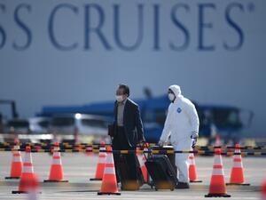 A passenger (L) disembarks from the Diamond Princess cruise ship - in quarantine due to fears of the new COVID-19 coronavirus - at the Daikoku Pier Cruise Terminal in Yokohama on February 19, 2020. AFP
