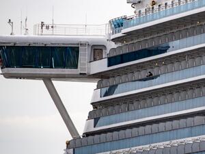 A passenger wearing a face mask looks out from the cabin of the Diamond Princess cruise ship, in quarantine due to fears of new COVID-19 coronavirus, at Daikoku pier cruise terminal in Yokohama on February 20, 2020. Two former passengers of the coronavirus-wracked Diamond Princess have died, local media reported, as fears mount about those who have left the ship after testing negative for the virus. Philip FONG / AFP