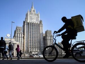 People walk and cycle past the Russian Foreign Ministry building in Moscow (AFP)
