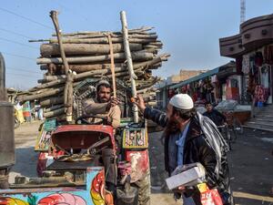 An Afghan refugee (R) distributes sweets to celebrate the 'reduction in violence' agreed earlier between Taliban, US and Afghan forces, in the Khurasan refugee camp on the outskirts of Peshawar on February 22, 2020. AFP