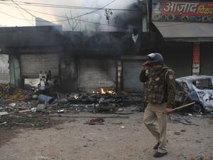A policeman walks past a burnt vehicle following clashes between supporters and opponents of a new citizenship law, at Bhajanpura area of New Delhi on February 24, 2020, ahead of US President arrival in New Delhi. AFP/File