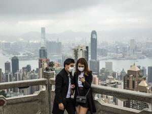 People wearing protective face masks visit the lookout of Victoria Peak in Hong Kong on February 25, 2020. The new coronavirus has peaked in China but could still grow into a pandemic, the World Health Organization warned, as infections mushroom in other countries. ISAAC LAWRENCE / AFP