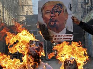 Demonstrators wave Palestinian flags as they burn effigies of US President Donald Trump and Israeli Prime Minister Benjamin Netanyahu during a protest against Trump's proposed Israeli-Palestinian peace plan, dubbed as the "deal of the century", outside an Israeli checkpoint in the flashpoint city of Hebron in the occupied West Bank on February 28, 2020. HAZEM BADER / AFP