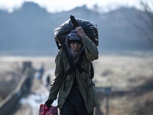 A migrant carries his belongings as he walks toward Meritsa river, near Edirne, to take a boat to attempt to enter Greece by crossing the river on March 1, 2020. AFP