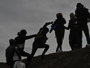 Migrants climb a hill as they gather near the Tunca river in the city of Edirne, northwest Turkey on March 5, 2020 waiting to resume their efforts to enter Europe near Pazarkule border gate. EU members on March 4, 2020 rejected what they said is Turkey's use of desperate migrants to pressure its neighbours -- and strongly backed Greece's border crackdown. The EU has scrambled to respond to the surge of migrants at the Greek border, where authorities say some 24,000 were stopped from entering between Februar