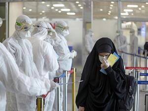 Medical staff in protective gears distribute information sheets to Iraqi passengers returning from Iran at Najaf International Airport on March 5, 2020. Iraqi health authorities announced the country's first two deaths from the new coronavirus, one in the capital Baghdad and the other in the autonomous Kurdish region. Haidar HAMDANI / AFP
