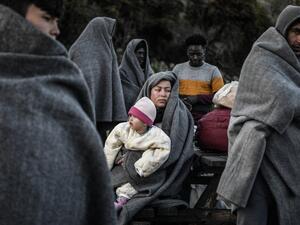 Migrants and refugees who arrived from Turkey to the Greek island of Lesbos on March 5, try to keep warm as they gather in the yard of a small church where they have spent the rainy night near Skala Sykamnias on March 6, 2020. A group of 42 refugees and migrants weave through coast guard patrols and arrived on the shores of Lebos during the evening of March 5. LOUISA GOULIAMAKI / AFP