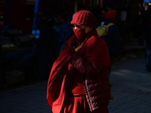 A Buddhist monk wearing facemasks amid fears of the spread of COVID-19 novel coronavirus, walks along a street market in McLeod Ganj near Dharamshala on March 9, 2020. Sajjad HUSSAIN / AFP