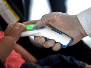 A security member checks the temperature of a passenger as a preventive measure against the spread of the new Coronavirus, COVID-19, at the Bonilla Aragon international airport in Palmira, Colombia, on March 10, 2020. Luis ROBAYO / AFP