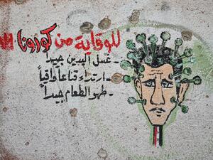 A graffiti portraying President Bashar al-Assad as the coronavirus is seen on the wall of a destroyed school in Binnish town in Syria’s northwestern Idlib province near the Turkish border, on March 10, 2020. AFP/File