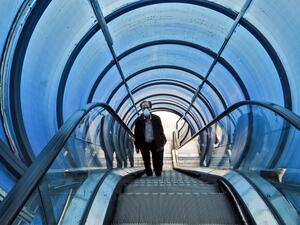A man wearing a protective face mask rides the escalator of a pedestrian overpass bridge in Iran's capital Tehran on March 14, 2020. STRINGER / AFP