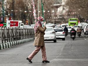 A woman wearing a protective face mask and latex gloves crosses a street in Iran's capital Tehran on March 14, 2020. STRINGER / AFP A woman wearing a protective face mask and latex gloves crosses a street in Iran's capital Tehran on March 14, 2020. STRINGER / AFP