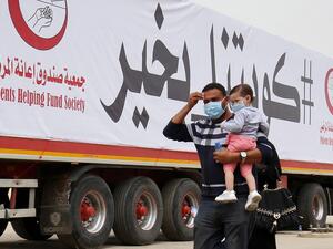 A man carries a toddler as they arrive at a Kuwaiti health ministry containment and screening zone for COVID-19 coronavirus disease for expatriates returning from Egypt, Syria, and Lebanon, in Kuwait City on March 15, 2020. YASSER AL-ZAYYAT / AFP