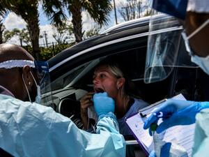 A medical personnel member takes samples of Lee Dinzik (29) at a "drive-thru" coronavirus testing lab set up by a local community center in West Palm Beach 75 miles north of Miami, on March 16, 2020. AFP/File