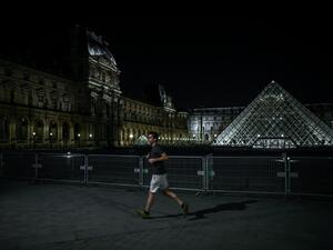 A man jogs past the Louvre Pyramid at night in Paris on March 18, 2020, as a strict lockdown came into in effect in France to stop the spread of COVID-19, caused by the novel coronavirus. A strict lockdown requiring most people in France to remain at home came into effect at midday on March 17, 2020, prohibiting all but essential outings in a bid to curb the coronavirus spread. The government has said tens of thousands of police will be patrolling streets and issuing fines of 135 euros ($150) for people wit