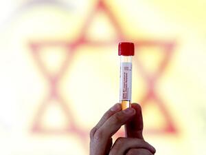 An Israeli medical personnel displays a sample taken from a driver at the Israeli Magen David Adom (MDA) national emergency service drive through complex for COVID-19 testing in Hayarkon Park's Rokach blvd parking lot in the coastal city of Tel Aviv on March 20, 2020. AFP