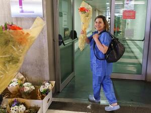 A health worker smiles after receiving a bouquet of flowers from a florist outside the Burgos Hospital (UBU) on March 21, 2020, in Burgos, in northern Spain. Spain reported a 32 percent spike in new deaths from the coronavirus, bringing the country total to 1,326 fatalities, the second highest in Europe after Italy. CESAR MANSO / AFP