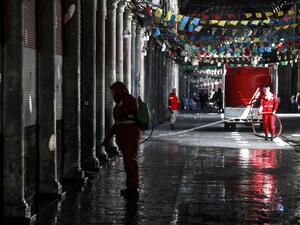A Syrian Red Crescent member sprays disinfectant along an alley of the historic Hamidiyah souk (market) in the old city of Syria's capital Damascus on March 22, 2020, as part of efforts against the COVID-19 coronavirus pandemic. LOUAI BESHARA / AFP