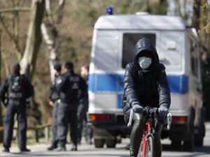 A cyclist wearing a protective mask bikes past a police patrol at the Tiergarten park in Berlin on March 23, 2020, amid the new coronavirus COVID-19 pandemic. Odd ANDERSEN / AFP