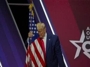 President Donald Trump rests his head on the flag of the United States of America at the annual Conservative Political Action Conference (CPAC) at Gaylord National Resort & Convention Center February 29, 2020 in National Harbor, Maryland. TASOS KATOPODIS / GETTY IMAGES NORTH AMERICA / AFP