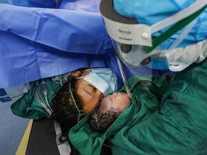 The new mother also wore a mask as her newborn baby girl was gently shown to her by medics in Xiehe hospital, Wuhan (AFP)