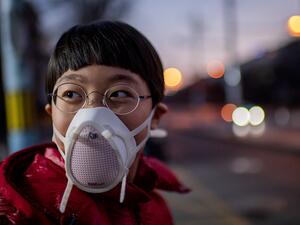 A child, wearing a protective mask to help stop the spread of a deadly virus which began in Wuhan, looks on in a street in Beijing on January 29, 2020. The number of confirmed cases in the new virus outbreak in China reached 5,974 on January 29, overtaking the number of people infected in the mainland by the SARS epidemic in 2002-3, as the death toll rose to 132. NICOLAS ASFOURI / AFP