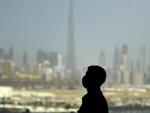 A man wearing a protective mask stands at a racetrack overlooking Dubai following the UAE's decision to postpone the upcoming Dubai Horse Racing amid the COVID-19 coronavirus pandemic, on March 23, 2020 in Dubai. KARIM SAHIB / AFP