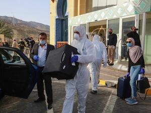 A worker helps a mask-clad woman with her baggage as she prepares to leave a Dead Sea resort where she has been quarantined for 14 days, approximately 60 kilometres sout of the Jordanian capital Amman on March 30, 2020. AFP/File A worker helps a mask-clad woman with her baggage as she prepares to leave a Dead Sea resort where she has been quarantined for 14 days, approximately 60 kilometres sout of the Jordanian capital Amman on March 30, 2020. AFP/File