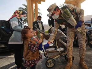 A Jordanian soldier greets people with flowers as they leave a Dead Sea resort where they have been quarantined for 14 days, approximately 60 kilometres sout of the Jordanian capital Amman on March 30, 2020. AFP