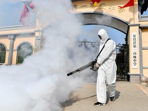 A volunteer sprays disinfectant at a school as the school prepares for students returning after the term opening was delayed due to the COVID-19 coronavirus outbreak, in Shangqiu in China's central Henan province on April 3, 2020. STR / AFP