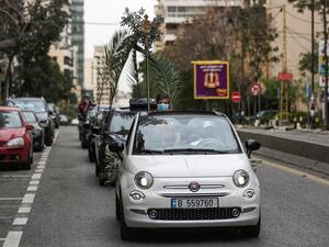 Lebanese Christian boyscouts wearing surgical masks, as a precaution against COVID-19 coronavirus disease, holding palm branches ride in a car procession marking Palm Sunday procession, according to the Western Gregorian calendar, in the capital Beirut on April 5, 2020. PATRICK BAZ / AFP