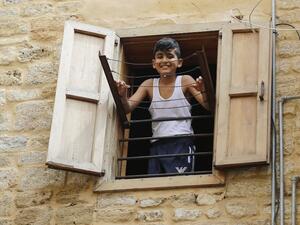 A Lebanese boy smiles as he looks out of a window during confinement at home due to the COVID-19 pandemic, in the historic part of the southern coastal city of Sidon (Saida), on April 6, 2020. Lebanon's President called on international donors to provide financial assistance to the crisis-hit country as it grapples with a severe economic downturn compounded by the novel coronavirus pandemic. JOSEPH EID / AFP