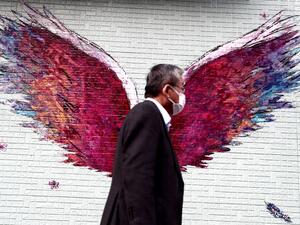 A man wearing a face mask amid concerns over the spread of COVID-19 coronavirus walks past a graffiti of wings in Tokyo on April 7, 2020. Japan's Prime Minister Shinzo Abe will on April 7 declare a state of emergency in parts of the country, including Tokyo, over a spike in coronavirus infections. Behrouz MEHRI / AFP