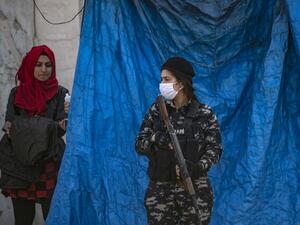A member of Kurdish Internal Security wearing a protective mask stands guard as Kurdish Red Crescent medics check a passenger for COVID-19 symptoms upon arrival from the Syrian capital, at a mobile site just outside Syria's Qamishli airport in the northeastern Hasakeh province, on April 7, 2020. AFP/File