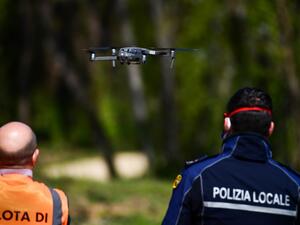 An officer of the municipal police (R), assisted by an instructor, pilots a DJI Mavic 2 Enterprise drone equipped with a thermal sensor for checking people's temperature on April 9, 2020 in Treviolo, near Bergamo, during the country's lockdown aimed at stopping the spread of the COVID-19 pandemic, caused by the novel coronavirus. Miguel MEDINA / AFP