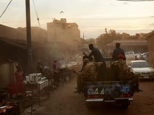 SSNPS (South Sudan National Police Service) police drive on pickup trucks past street vendors while patrolling the streets of Juba, South Sudan on April 9, 2020. South Sudanese police are enforcing a night curfew which was recently introduced by the government in order to slow the spread of the COVID-19 coronavirus. Alex McBride / AFP
