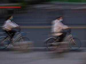 Women wearing face masks ride bicycles on a street in Wuhan, in China's central Hubei province on April 11, 2020. Hector RETAMAL / AFP